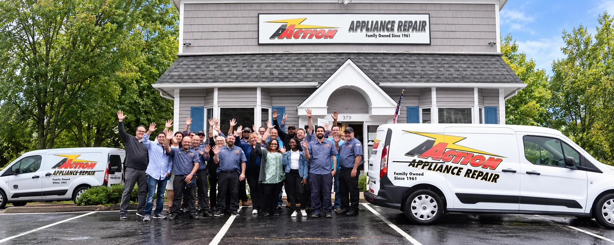 The Action Appliance Repair team waving outside their office with company service vans