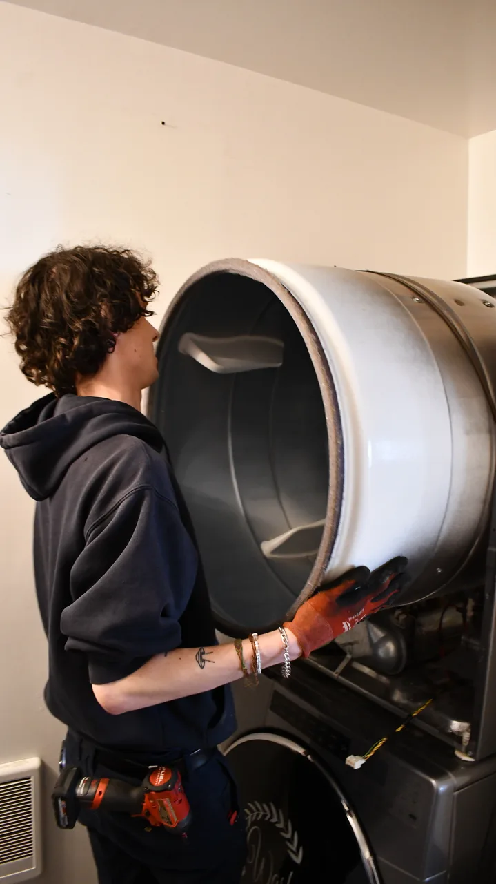 A technician working on the open drum of a clothes dryer