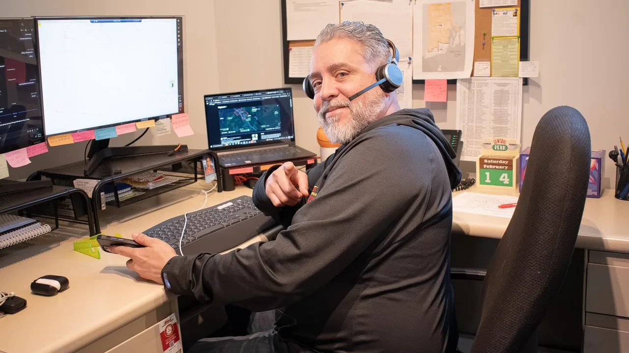 An Action office team member wearing a headset, working at a desk with multiple monitors