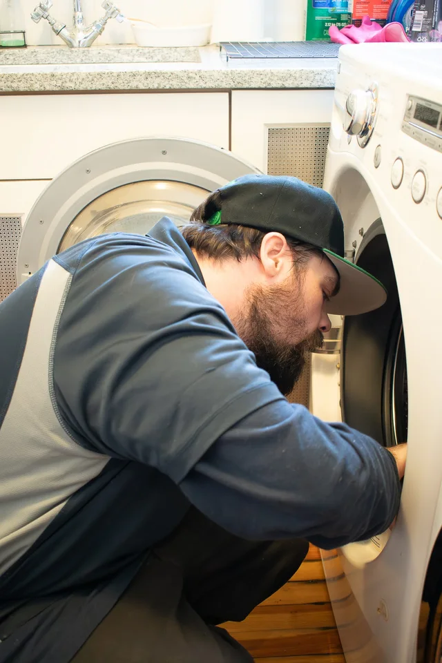 An Action technician working inside an open washing machine
